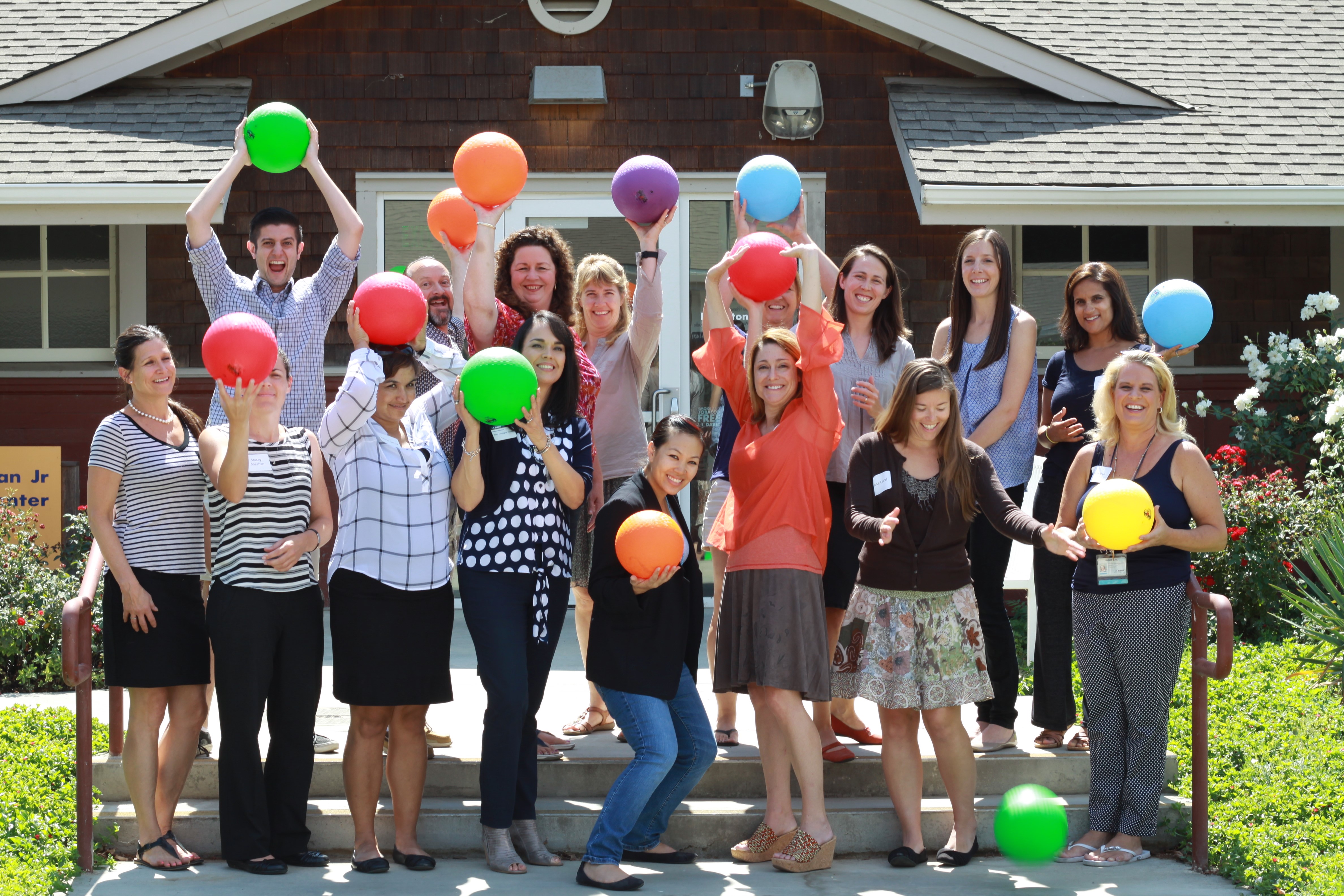 group of smiling people holding colorful balloons