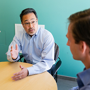 "man talking to a male colleague during a meeting"