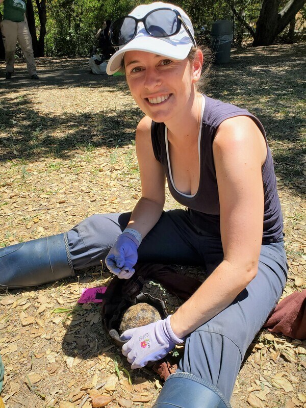 Sonja Wild sits on the ground outside and treats a squirrel.