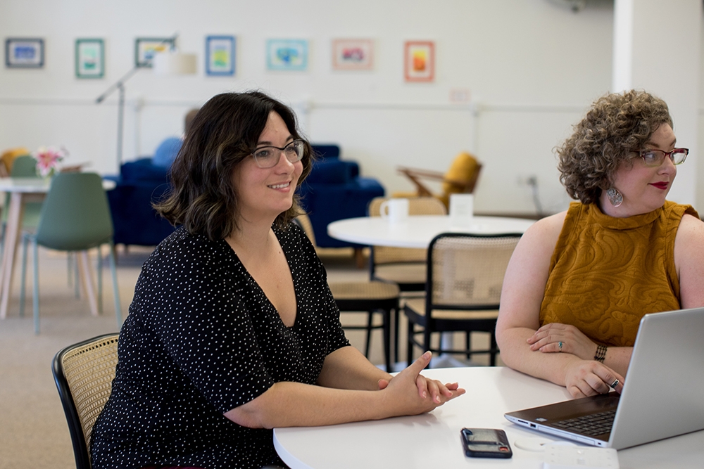 woman sitting with colleague and smiling