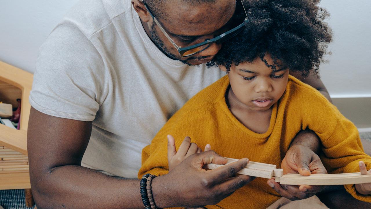 parent and child working to piece together a train set