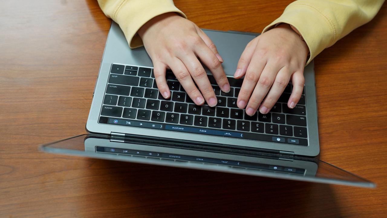 Persons hands typing on laptop.