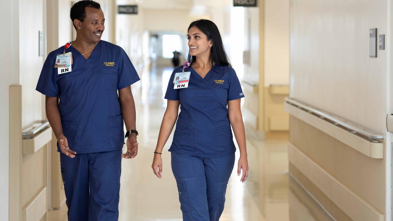 Two registered nurses walking side by side down the hallway