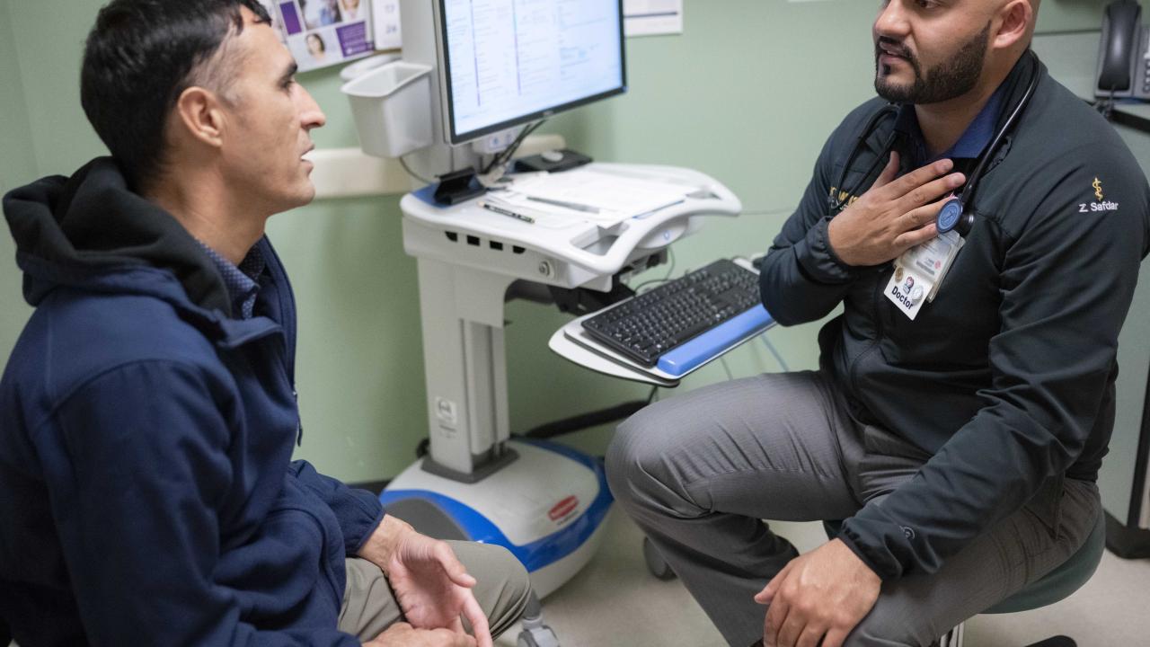 Doctor and patient are speaking sitting across from one another.  