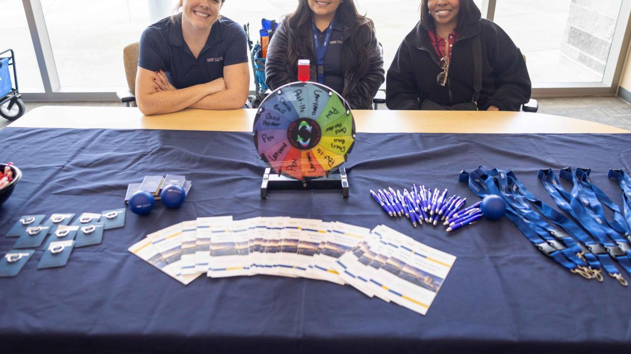 Rachel Henry, Melissa Cuevas, and Jasmine Cusic from the Workplace Violence Prevention team are seated at a table with materials in front of them.  