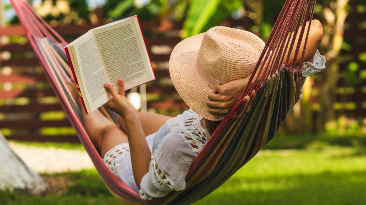 person in hammock reading book and relaxing.