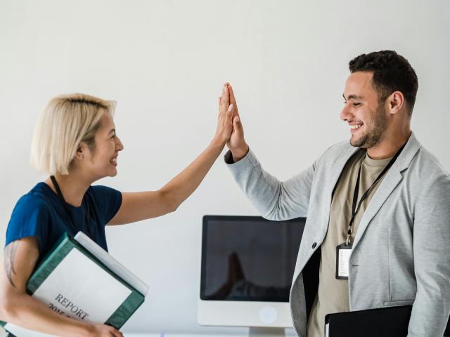 A man and woman highfive in the office.