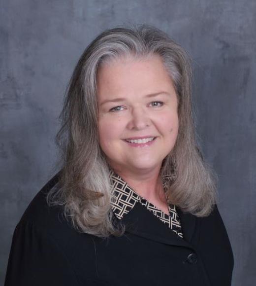 Photo of Michele Haynes in a black shirt and smiling.