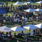 Aerial view of vendor pop-up tents on Hutchison Field at UC Davis, with people visiting each tent.