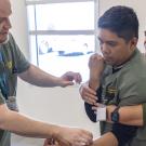 Three people in green scrubs practicing arm splinting, focused clinical training photo