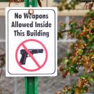 Photo of a gun with no weapons allowed text. 