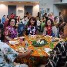A group of people sitting at a round table smile at the camera.