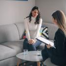 Two women sit in a cozy room, engaging in a conversation.