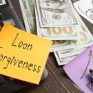 Sticky note that reads "Loan Forgiveness" alongside some US currency and a calculator